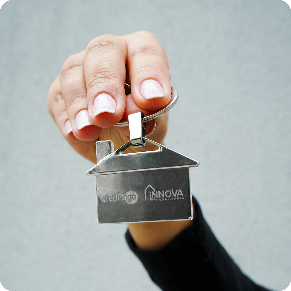 Mão segurando um chaveiro de casa com a logo da Innova