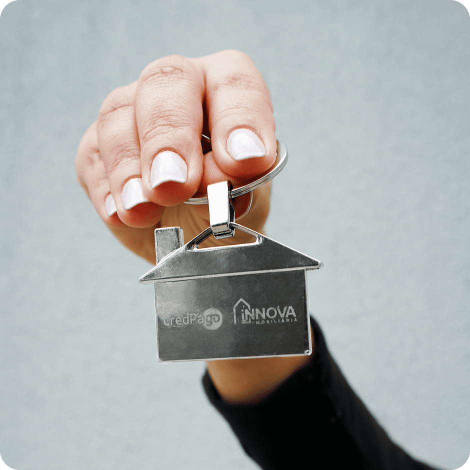 Mão segurando um chaveiro de casa com a logo da Innova